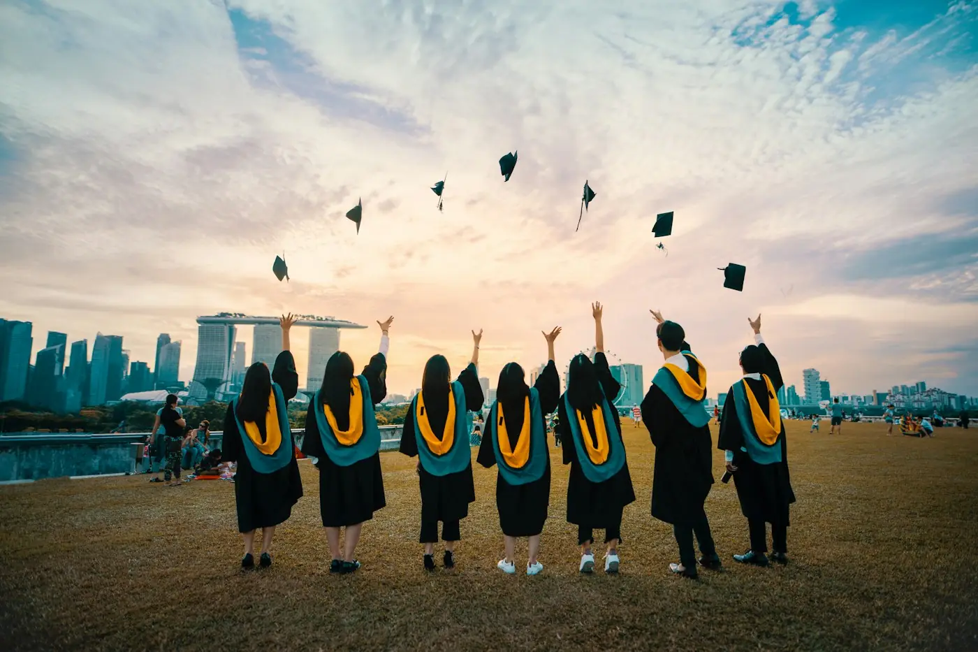Graduates throwing their caps in the air at sunset